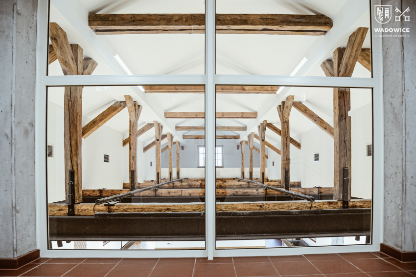 fot. Urząd Miejski w Wadowicach Poddasze budynku dworca PKP widoczne przez okno. Konstrukcja z drewninaych belek, biały sufit.