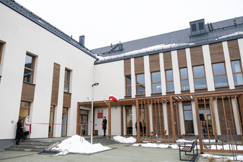 Wysoki, nowoczesny, kremowy budynek z elementami drewnianymi.