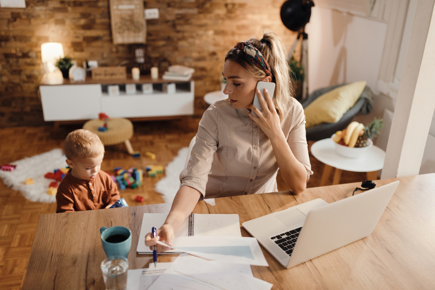 Mama pracuje zdalnie w domu. Na podłodze bawiące się małe dziecko.