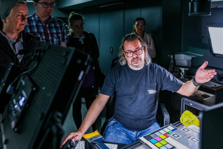 Mężczyzna w pracowni digitalizacji opowiada o działaniu znajdującego się tam sprzętu.