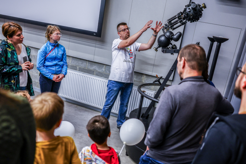 Mężczyzna pokazuje grupce osób duży teleskop w planetarium.