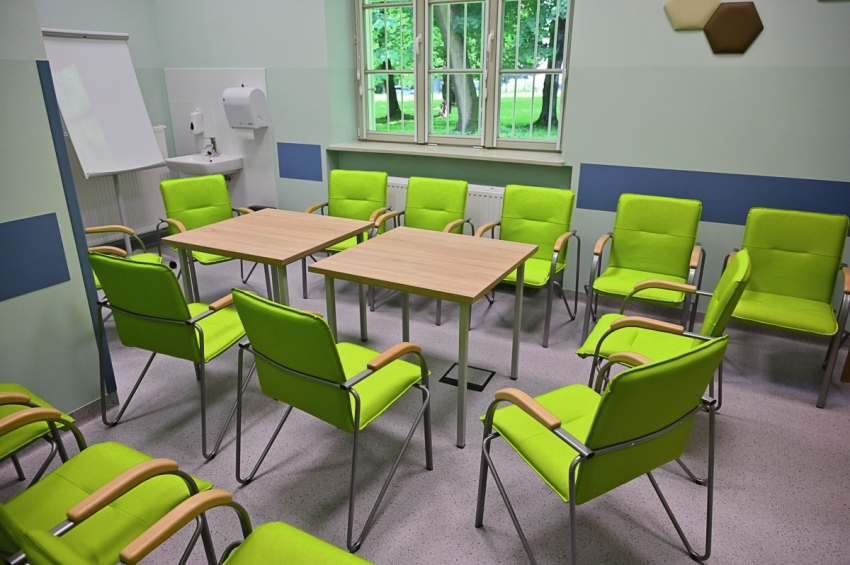 Sala w szpitalu na spotkania grupowe. Stół i kilkanaście krzeseł. Tablica do pisania.