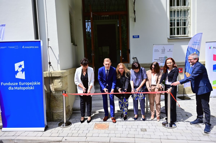 Kilka osób przecina wstęgę przed wejściem do nowego budynku na terenie parku.