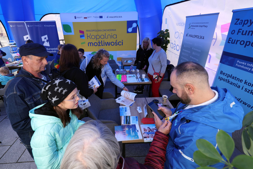 Konsultant Punktu Informacyjnego Funduszy Europejskich rozmawia z uczestnikami wydarzenia.