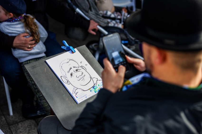 Mężczyzna z karykaturą uczestnika pikniku.