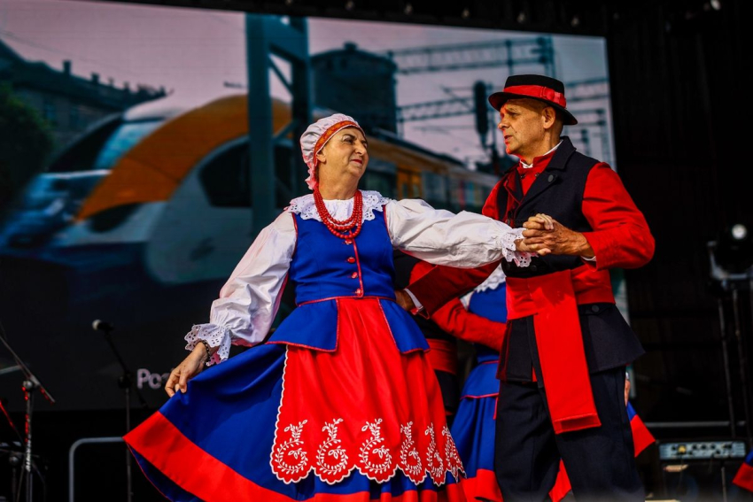 Para seniorów w strojach ludowych tańczy na scenie.