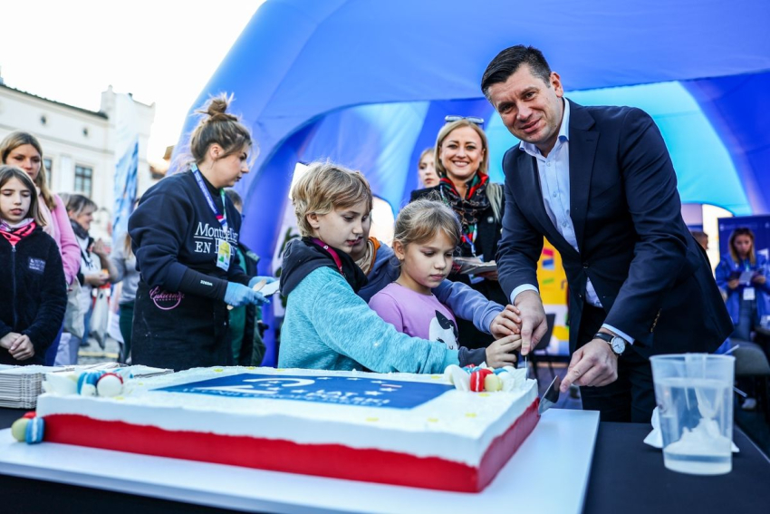 Marszałek Małopolski kroi tort wraz z trójką dzieci.