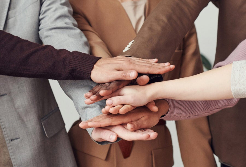 Dłonie kilku osób złożone jedne na drugich.