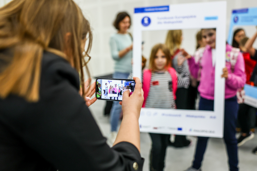Dzieci pozują w fotoramce Funduszy Europejskich.