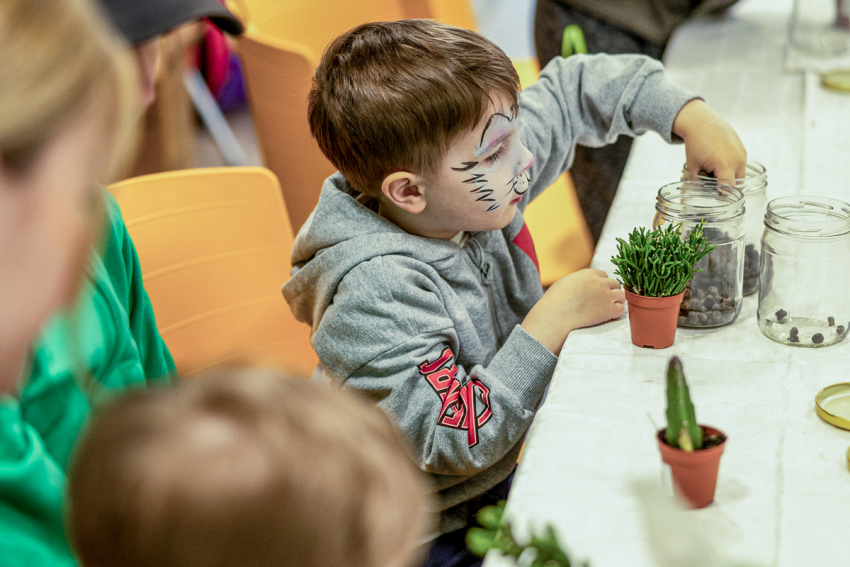 Chłopczyk przesadza roślinkę do słoika.
