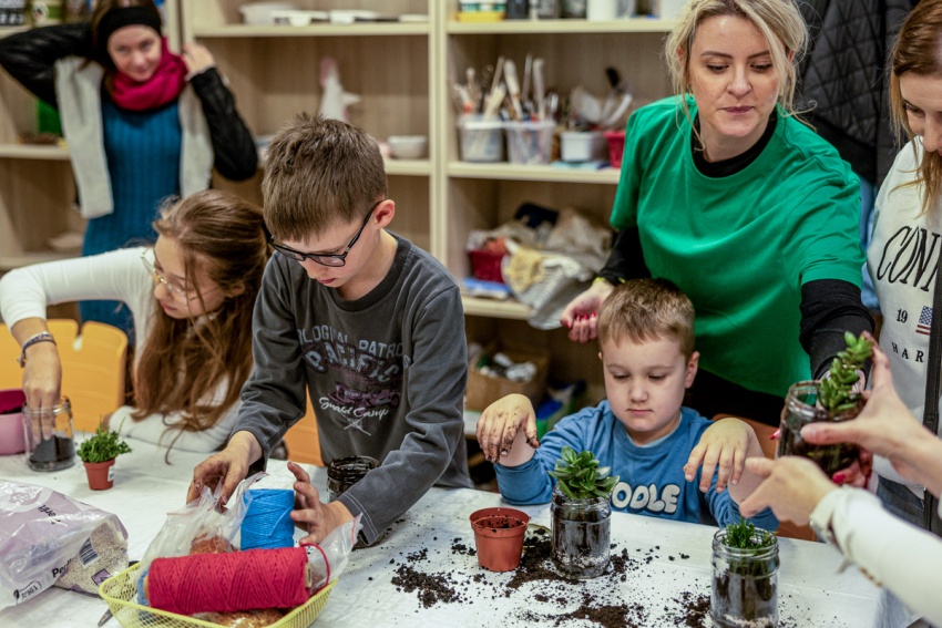 Dzieci tworzą kompozcyje roślinne w słoikach.