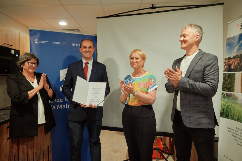 Uczestnicy wydarzenia biją brawo dla osoby, który otzrymała promesę.