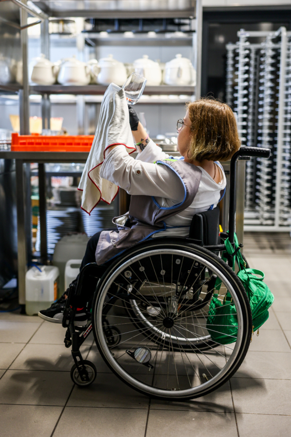 Dziewczyna na wózku inwalidzkim wyciera kieliszki do wina.