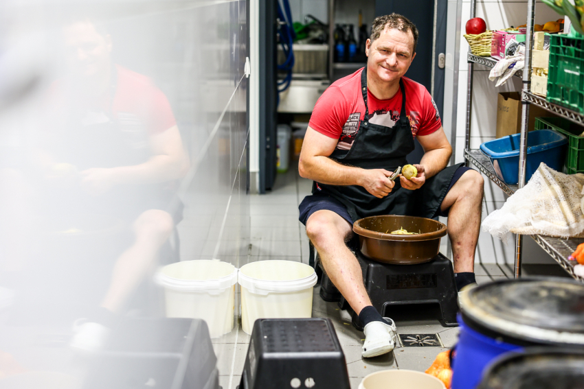 Mężczyzna obierający ziemniaki.