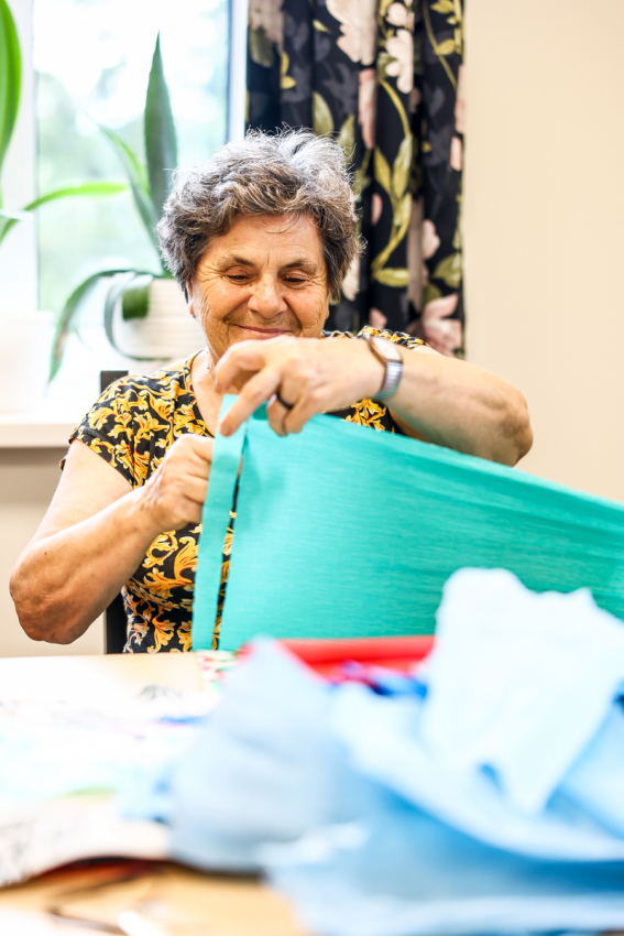 Seniorka wycina kształty z bibuły.