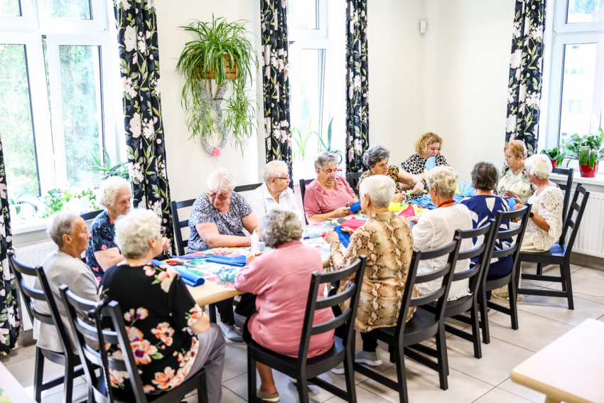 Seniorzy przy stole biorą udział w warsztatach kreatywnych.