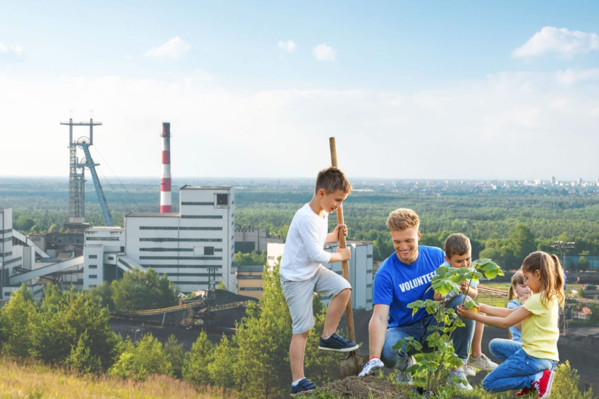 Tata z dziećmi sadzą drzewka.