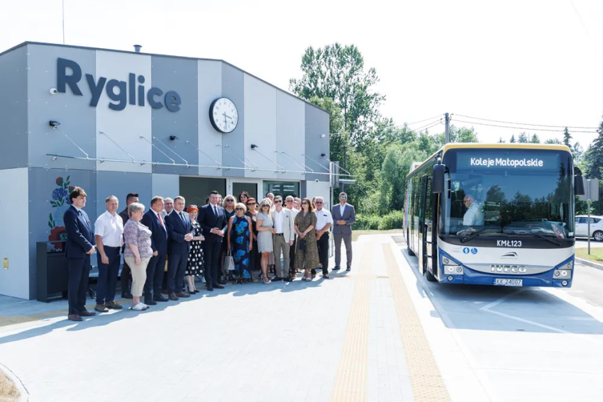 Uczestnicy wydarzenia przed poczekalnią. Obok autobus.