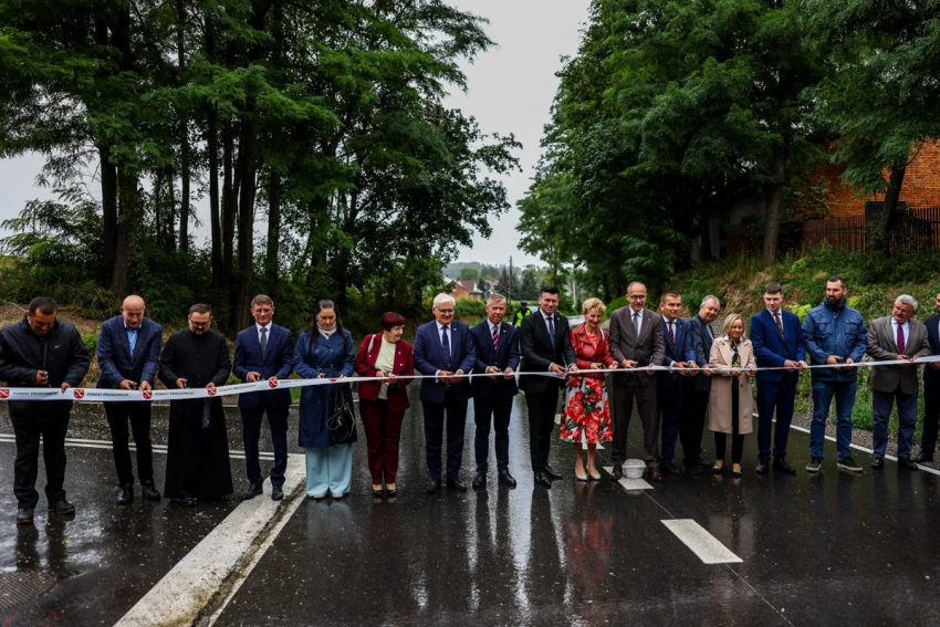 Uczestnicy wydarzenia przecinają wstęgę na znak otwarcia drogi. Wśród nich Marszałek Łukasz Smółka.