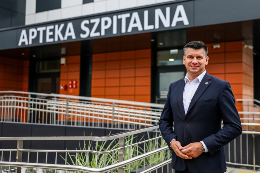 Marszałek Łukasz Smółka przed budynkiem apteki.