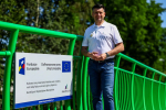 Marszałek Łukasz Smółka onok tablic informacyjnej Funduszy Europejskich.