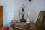 Lampa naftowa, figurka Matki Boskiej, książki i czarno biała fotografia.