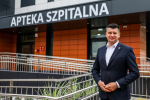 Marszałek Łukasz Smółka przed budynkiem apteki.