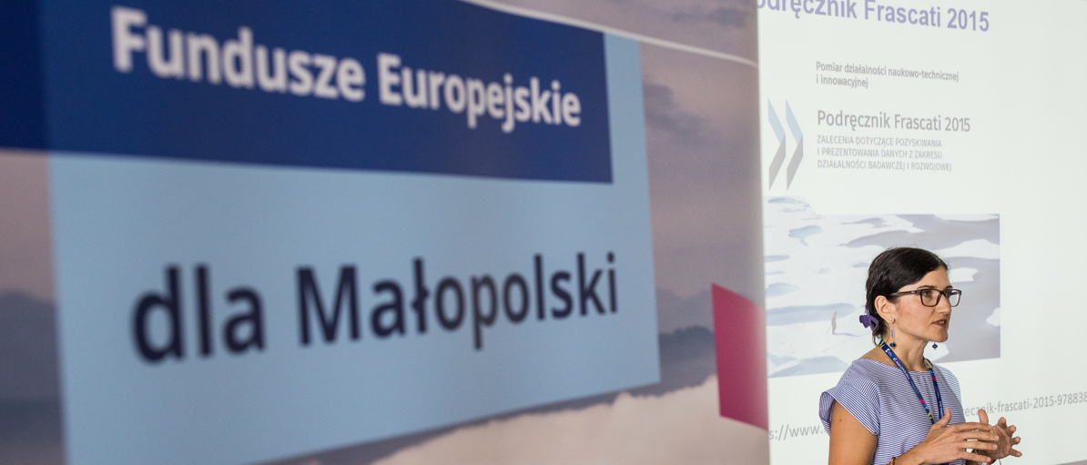 Roll-up z napisem Fundusz Europejskie dla Małopolski wystawiony obok prowadzącej szkolenie.
