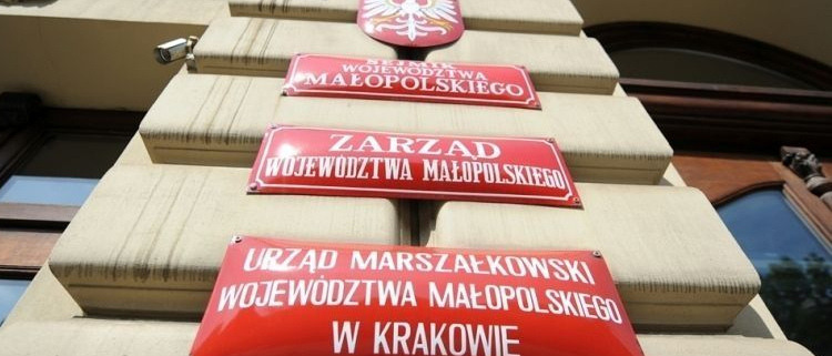 Fragment budynku z czerwonymi tablicami informującymi, że mieści się w nim Urząd Marszałkowski Województwa Małopolskiego.