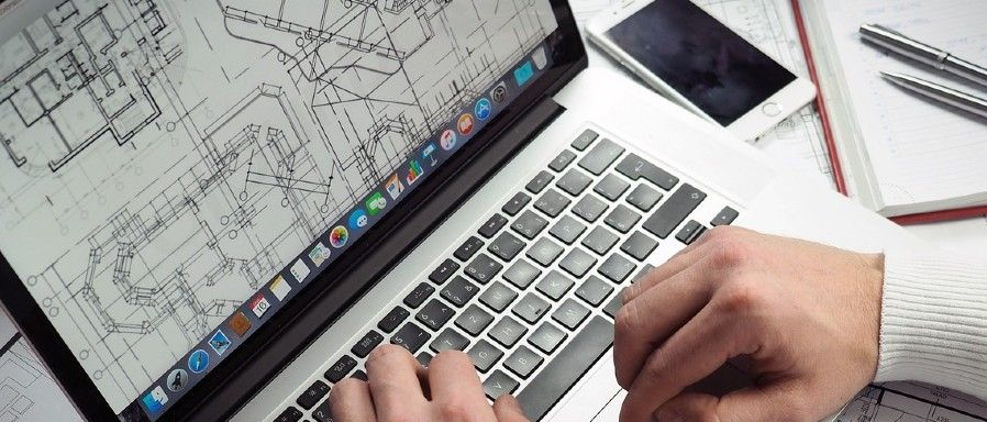 Dłonie mężczyzny na otwartym laptopie.