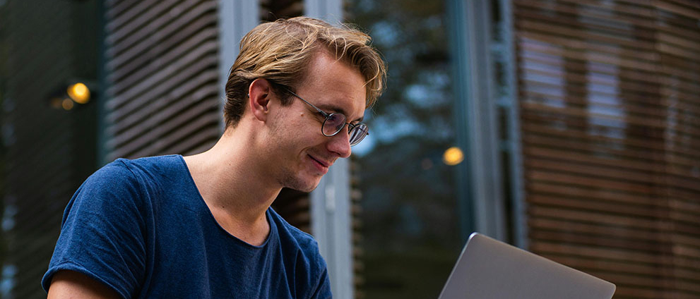 Młody chłopak pochylony nad laptopem.