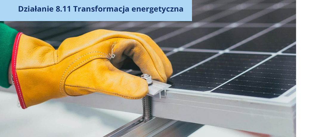 Dłoń w rękawicy zakładająca śrubę na panel fotowoltaiczny.