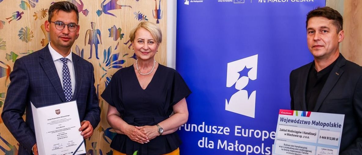 Iwona Gibas z Zarządu Województwa Małopolskiego oraz przedstawiciele miasta i gminy Miechów prezentujący wspólnie przekazany uroczyście dokument i symboliczny czek