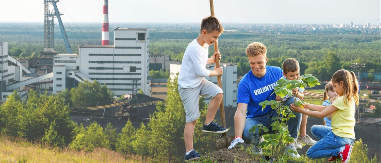 Tata z dziećmi sadzą drzewka.