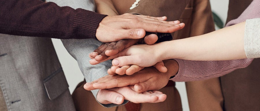 Dłonie kilku osób złożone jedne na drugich.