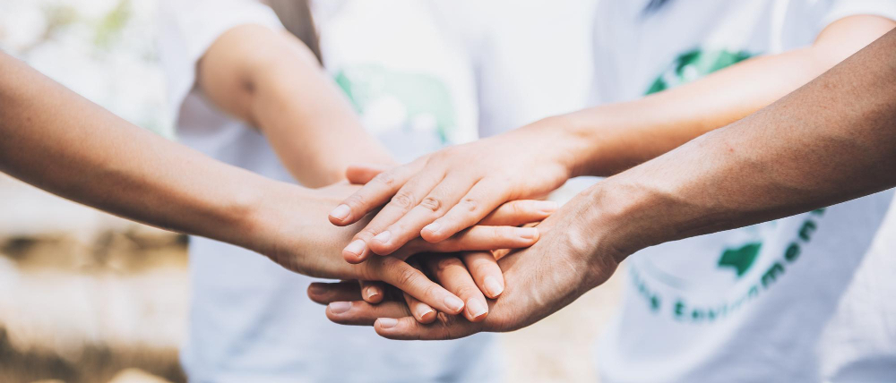 Dłonie kilku osób złożone jedne na drugich.