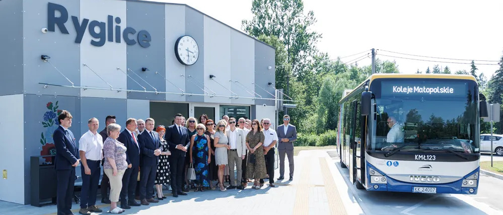 Uczestnicy wydarzenia przed poczekalnią. Obok autobus.