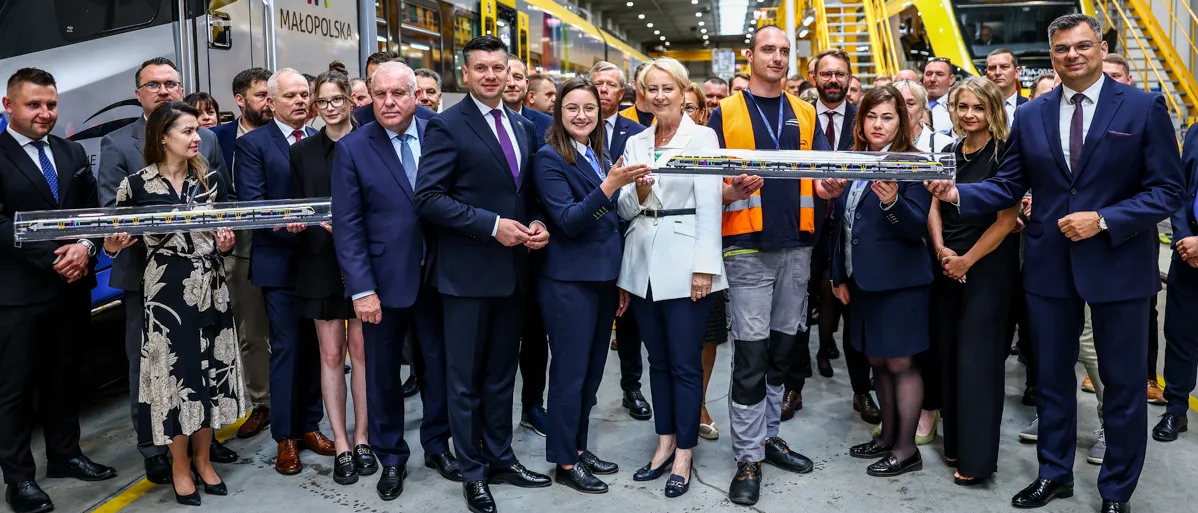 Uczestnicy wydarzenia przy składzie kolejowym. Wśród nich, Marszałek Łukasz Smółka, Pani Iwona Gibas, Wicemarszałek Ryszard Pagacz.