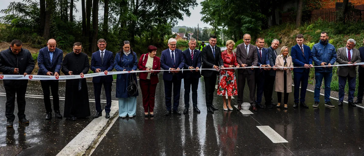 Uczestnicy wydarzenia przecinają wstęgę na znak otwarcia drogi. Wśród nich Marszałek Łukasz Smółka.