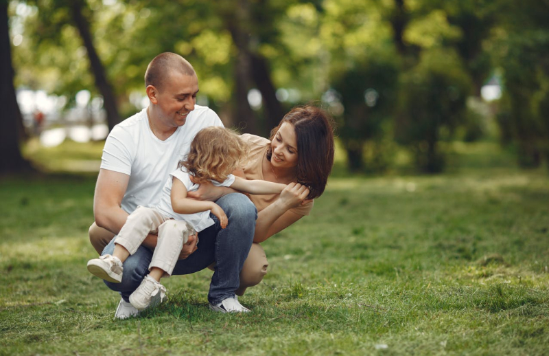 Rodzice z małą dziewczynką w parku.